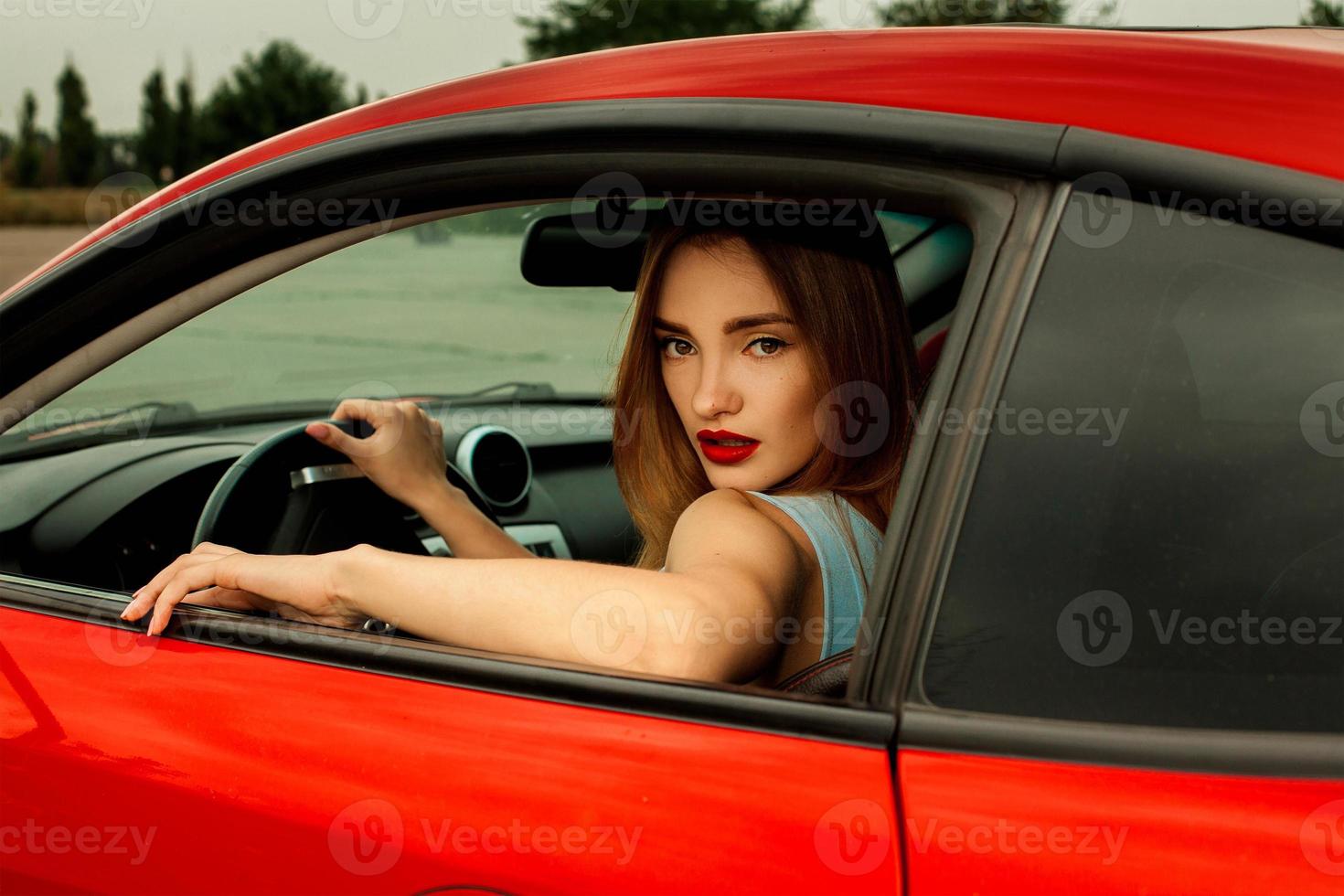 chica con buen maquillaje conduciendo un auto rojo foto