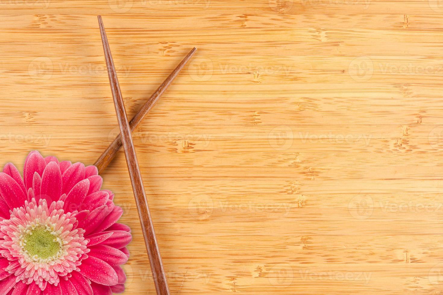 gerber daisy y palillos sobre un fondo de bambú foto