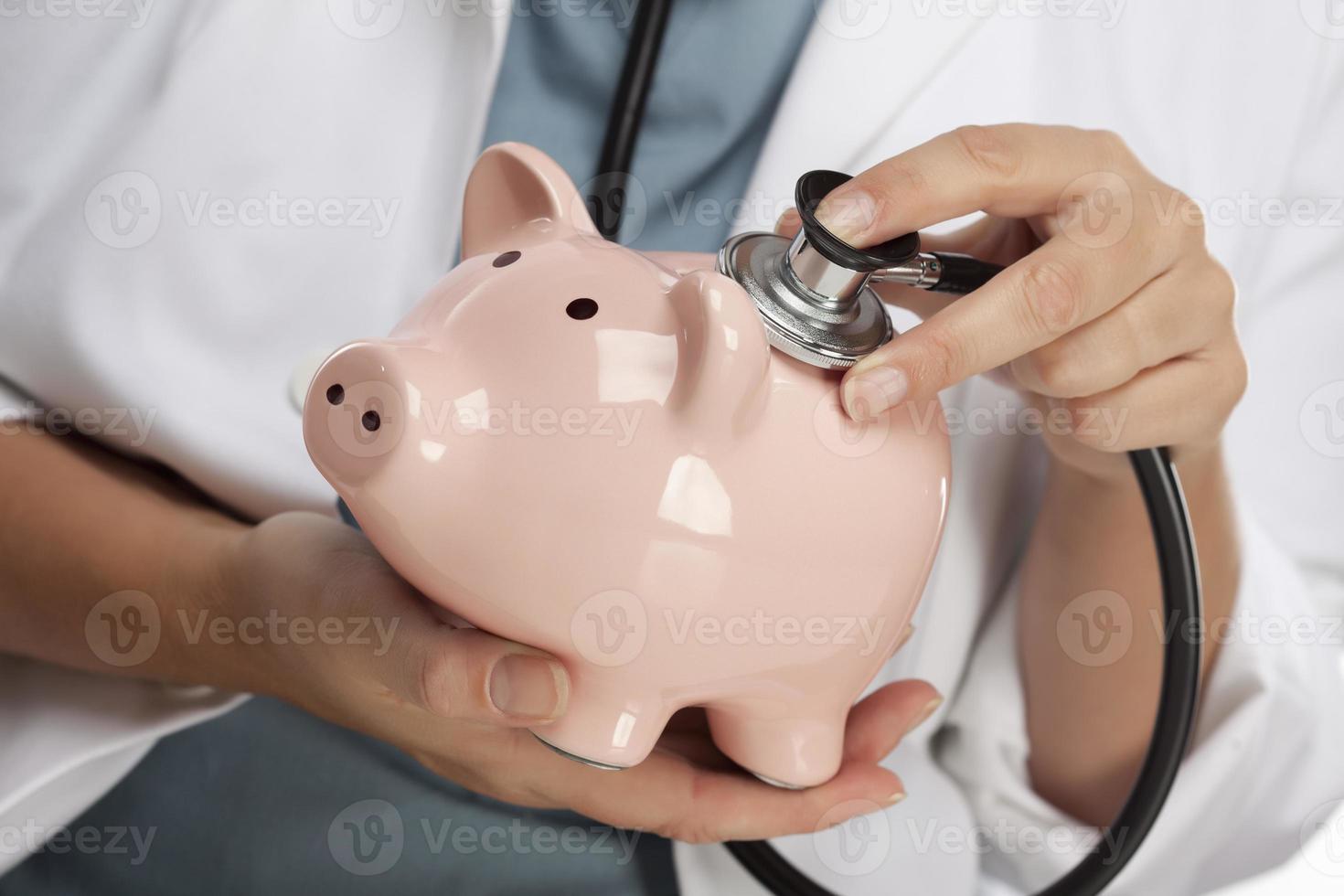 Doctor Holding Stethoscope to Piggy Bank photo