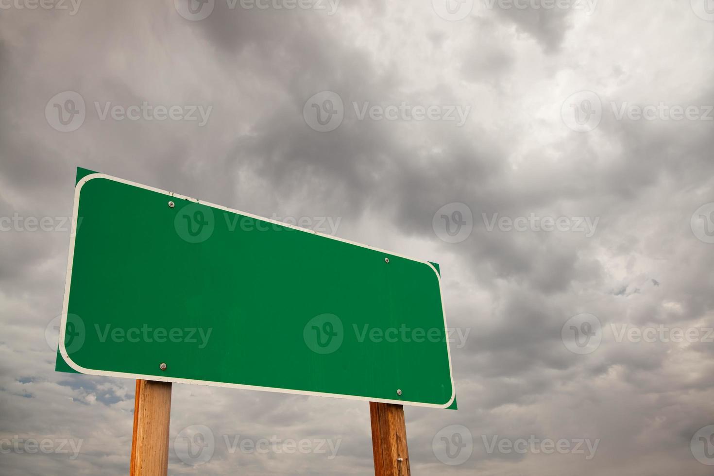 señal de carretera verde en blanco sobre nubes de tormenta foto