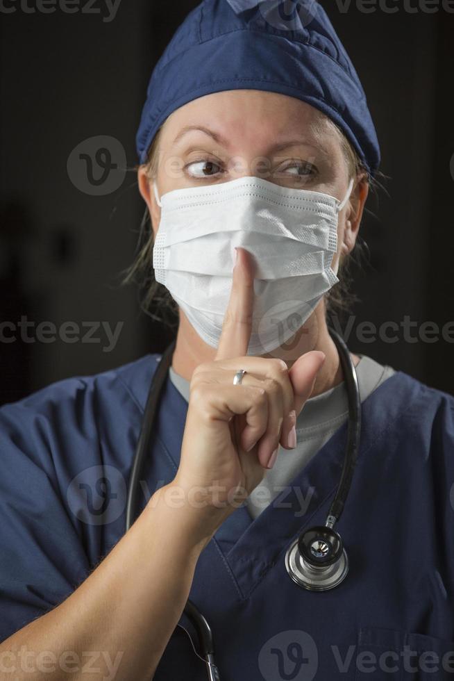 Secretive Female Doctor with Finger in Front of Mouth photo