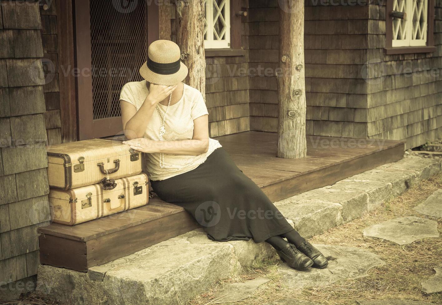 Distressed 1920s Girl Near Suitcases on Porch with Vintage Effect photo