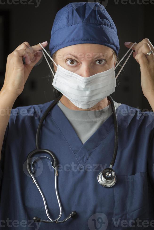 Female Doctor or Nurse Putting on Protective Face Mask photo