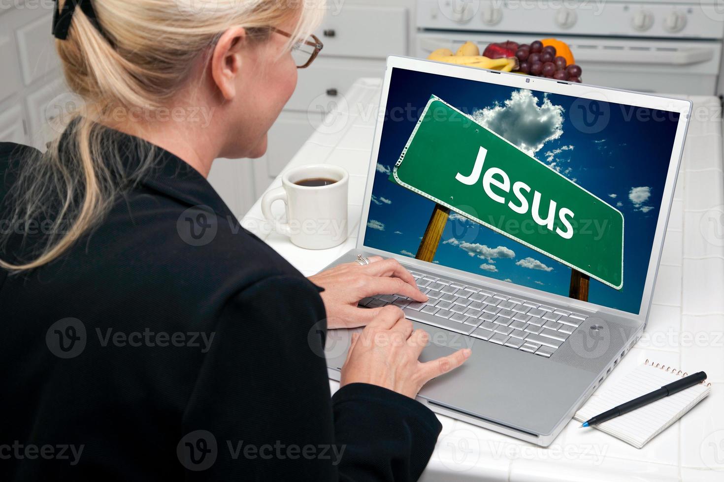 Woman In Kitchen Using Laptop with Jesus Sign photo