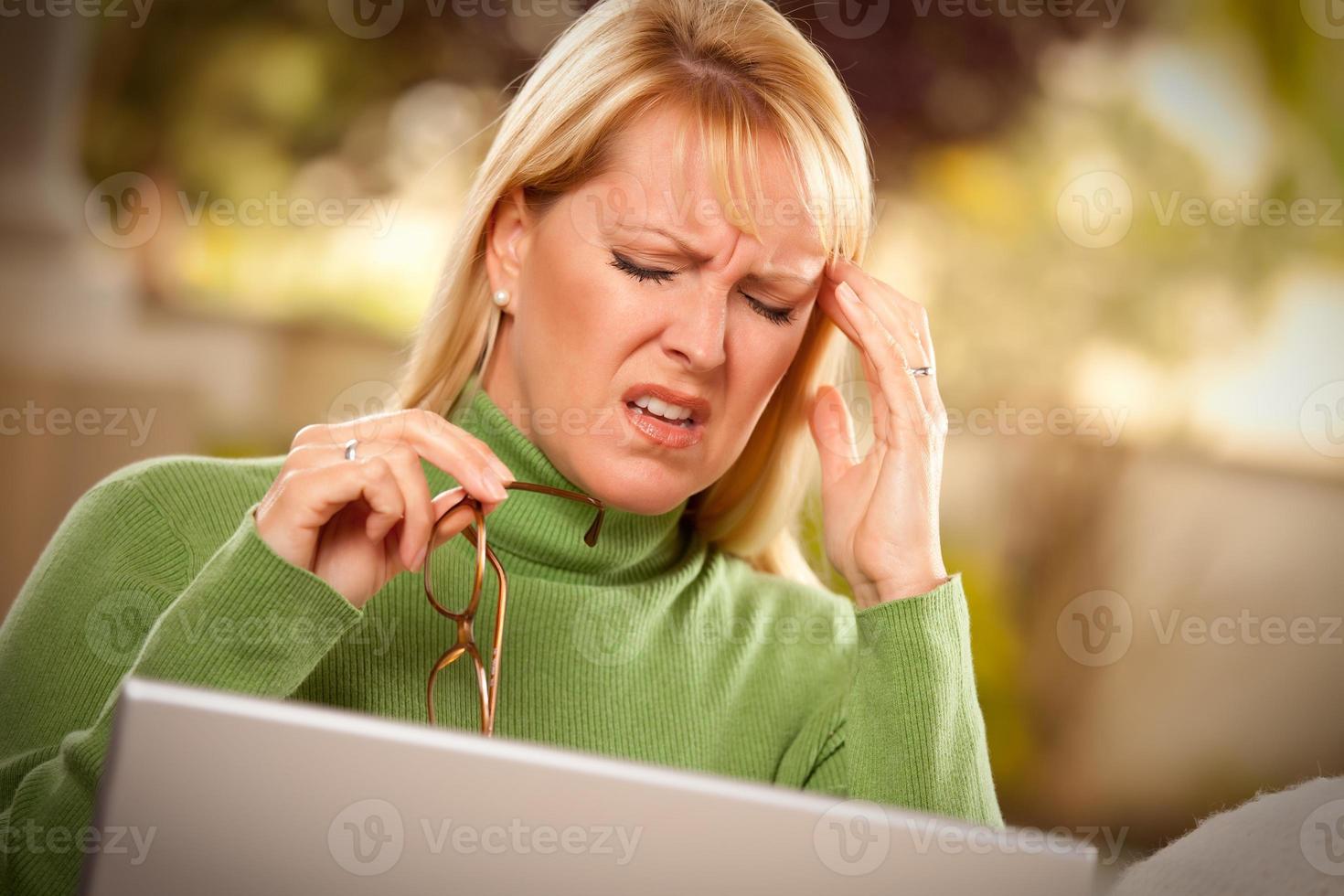 Grimacing Woman Using laptop Suffering a Headache photo