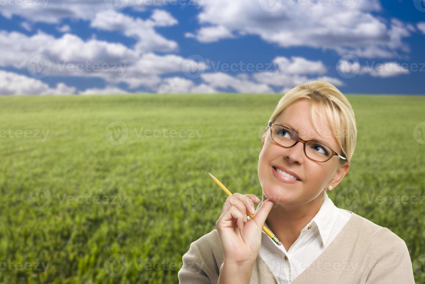 Contemplative Woman in Grass Field Looking Up and Over photo
