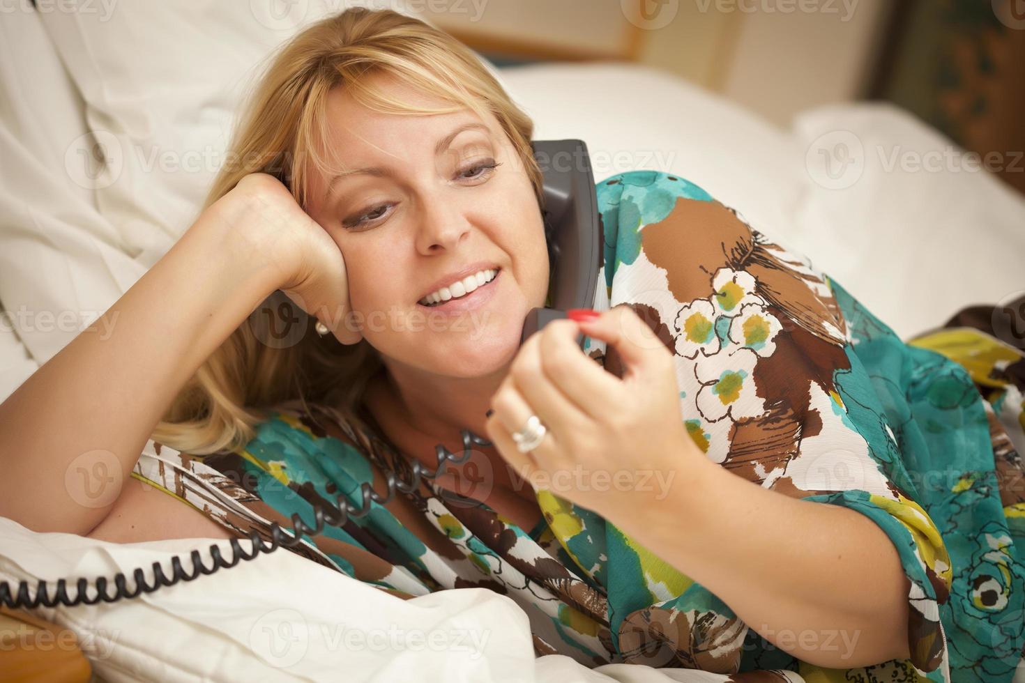 Woman Laying on Her Bed Using the Telephone photo