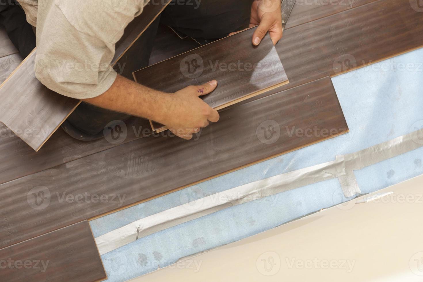 hombre instalando nuevos pisos de madera laminada foto