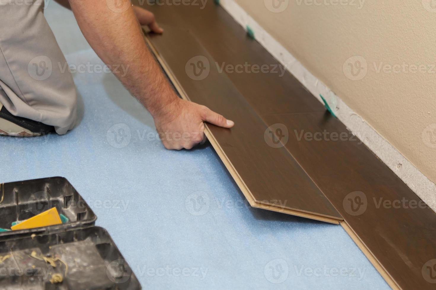 hombre instalando nuevos pisos de madera laminada foto