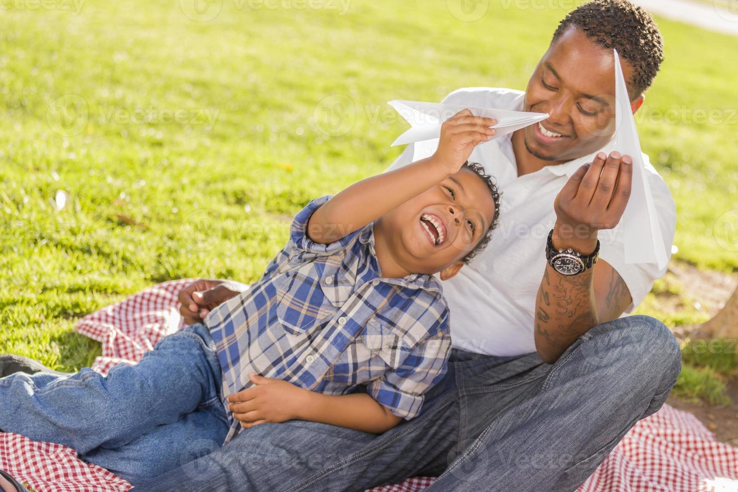 Mixed Race Father and Son Playing with Paper Airplanes photo
