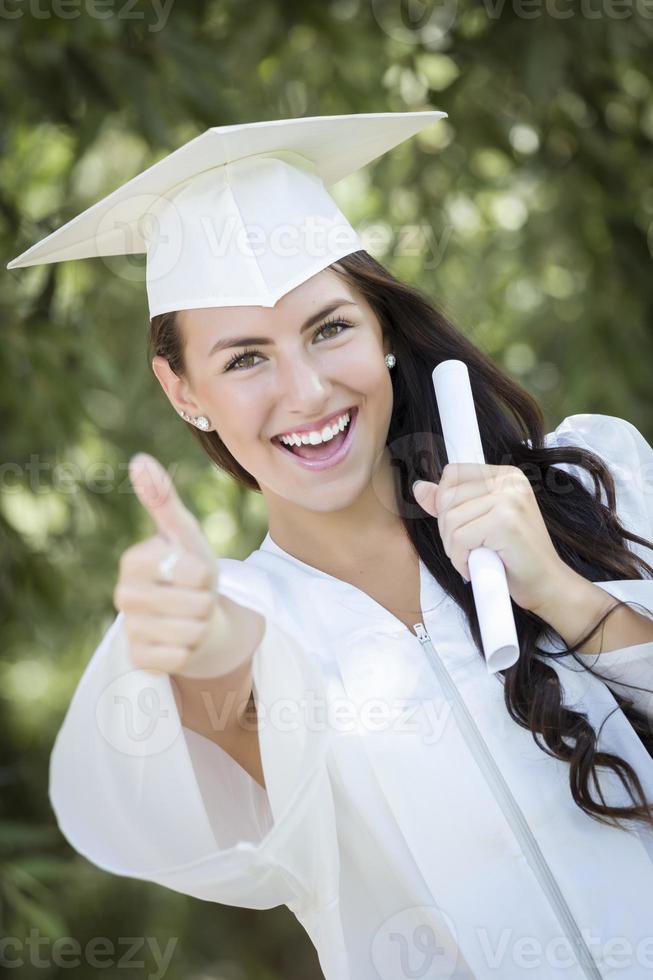 niña de raza mixta graduada en toga y birrete con diploma foto