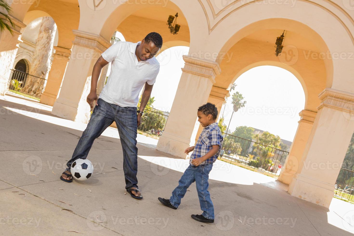 Mixed Race Father and Son Playing Soccer in the Courtyard photo