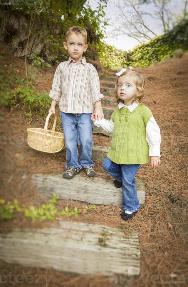 dos niños bajando escalones de madera con una cesta afuera. foto