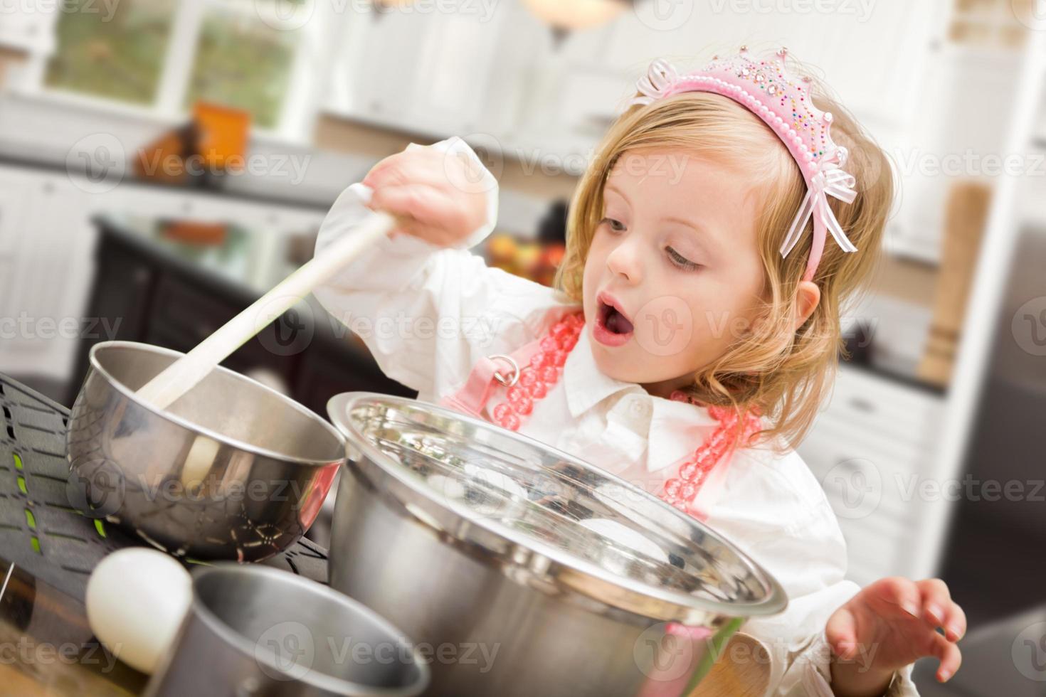 Linda niña jugando a cocinar con ollas y sartenes en la cocina foto