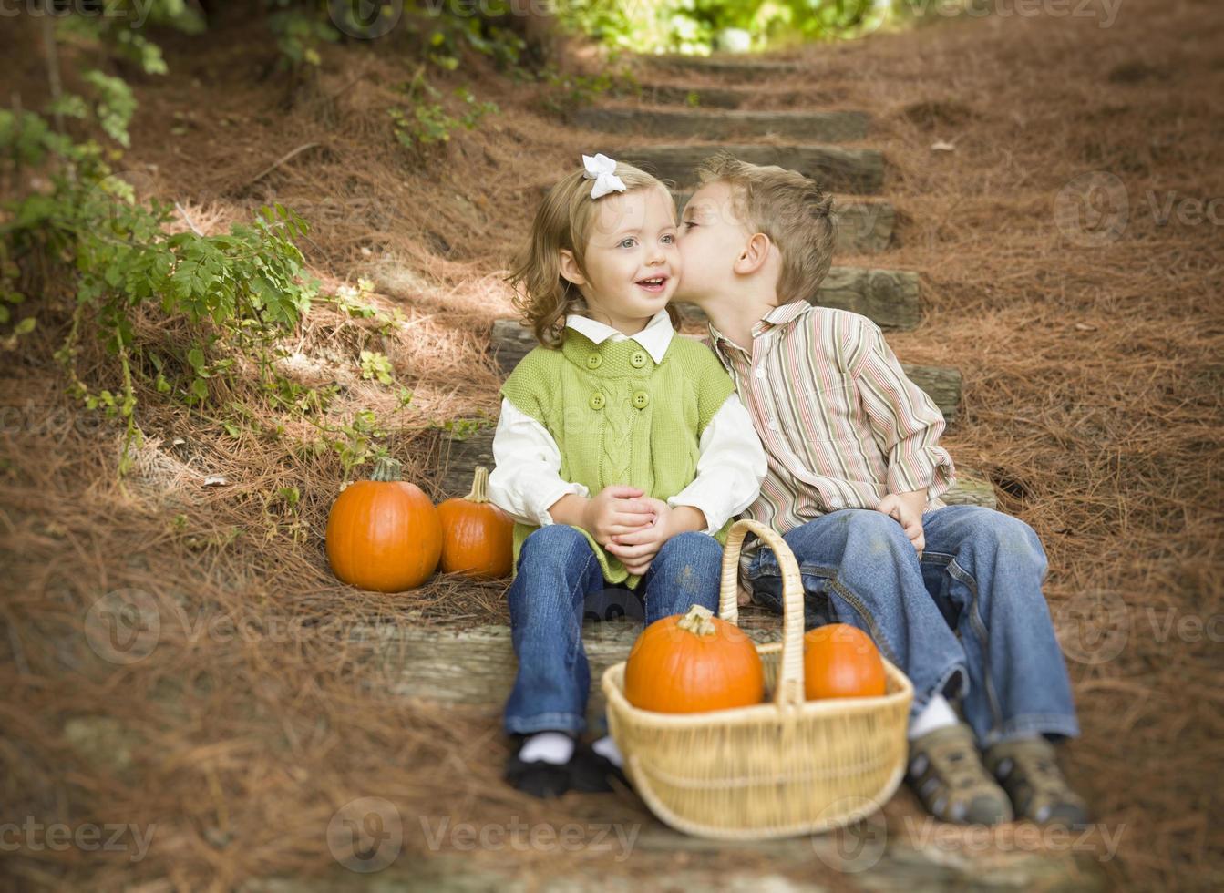 hermano y hermana niños en escalones de madera con calabazas susurrando foto