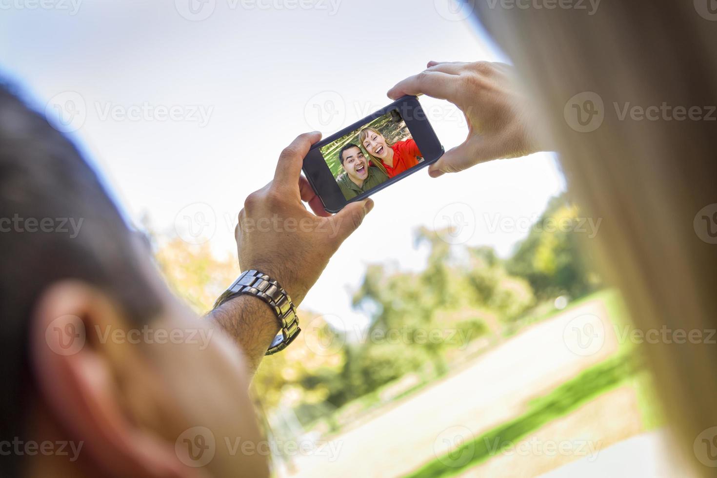 pareja de raza mixta tomando autorretrato en el parque foto