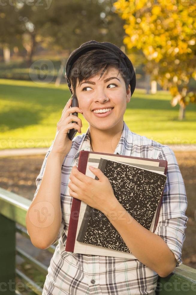 Mixed Race Female Student Holding Books and Talking on Phone photo