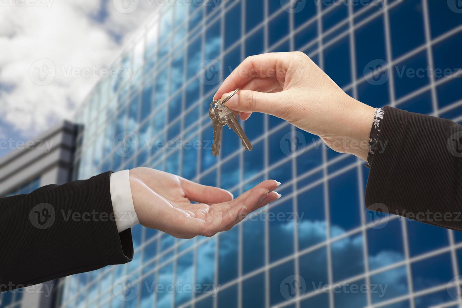 mujer entregando las llaves frente al edificio corporativo foto