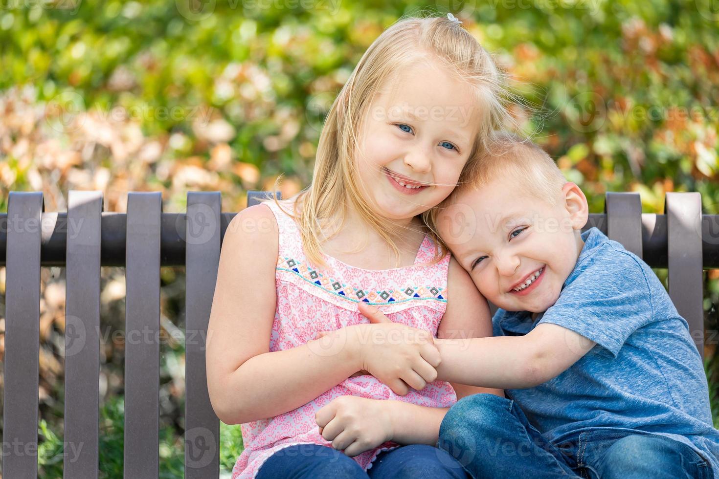 hermana joven y hermano divirtiéndose en el banco en el parque foto