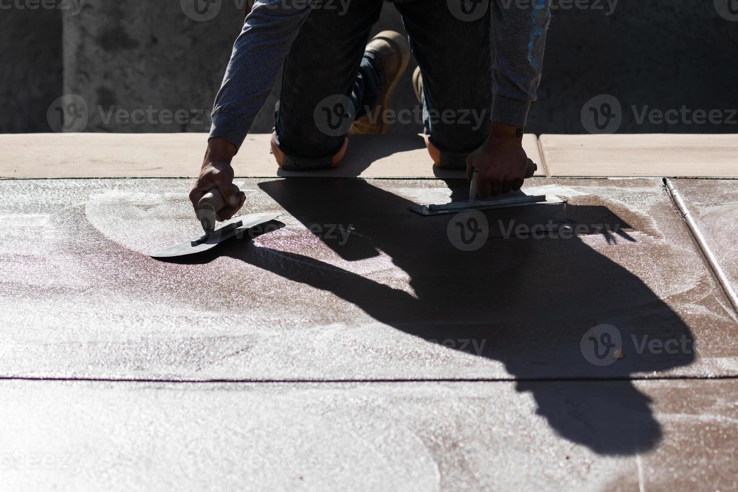 trabajador de la construcción alisando cemento húmedo con herramientas de paleta foto