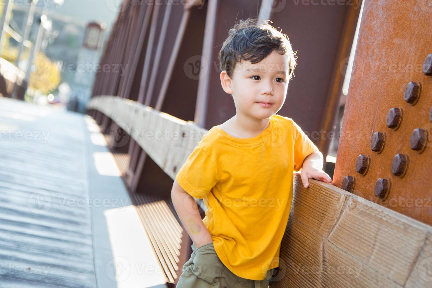 Mixed Race Chinese and Caucasian Boy Playing Alone on Bridge photo
