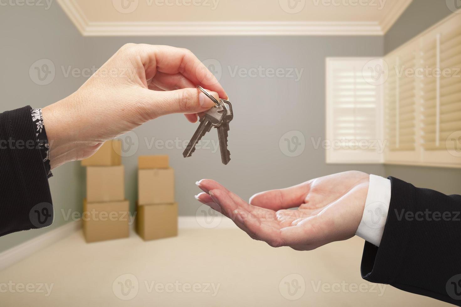 mujer entregando las llaves de la casa dentro de una habitación gris vacía foto