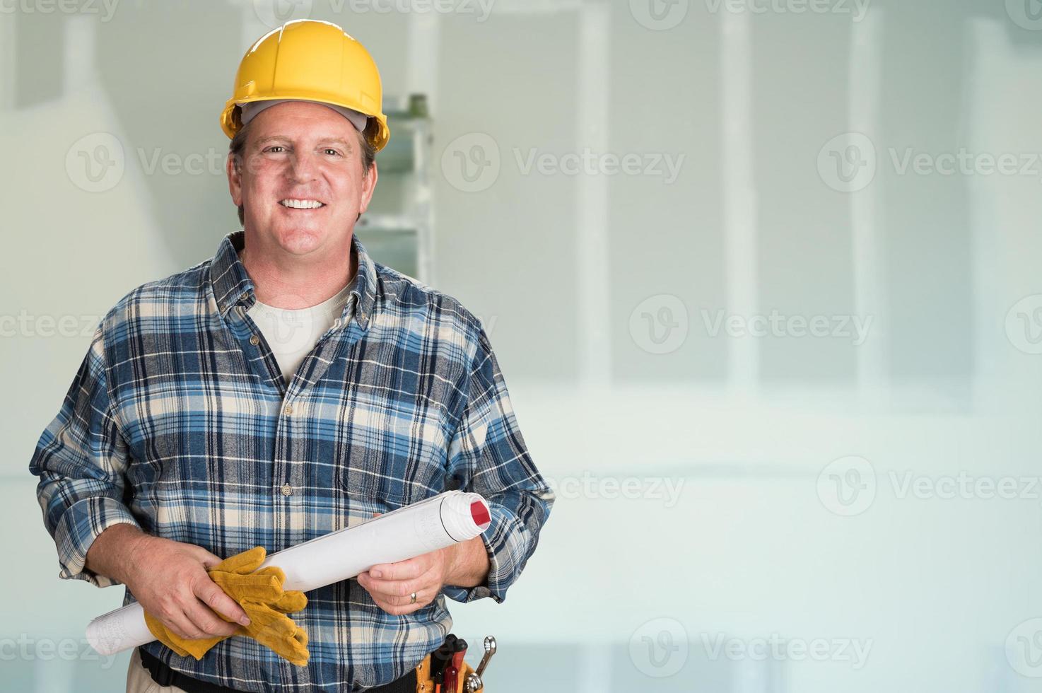 Contractor with Plans and Hard Hat In Front of Drywall. photo