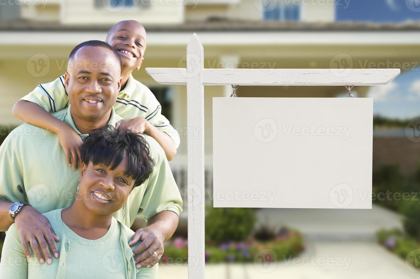 African American Family In Front of Blank Real Estate Sign and House photo