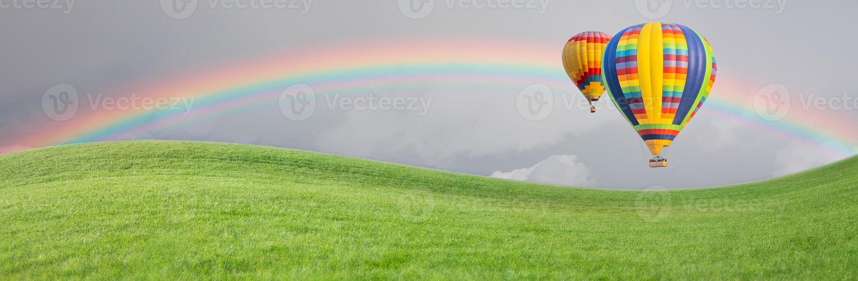 Hot Air Baloons Drift Above Grass Field with Rainbow in the Sky. photo