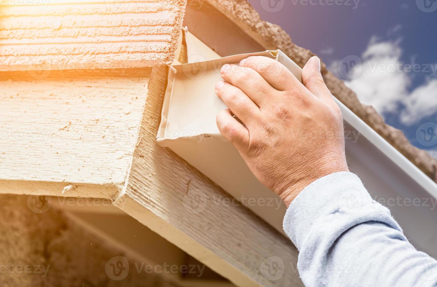 Worker Attaching Aluminum Rain Gutter to Fascia of House photo