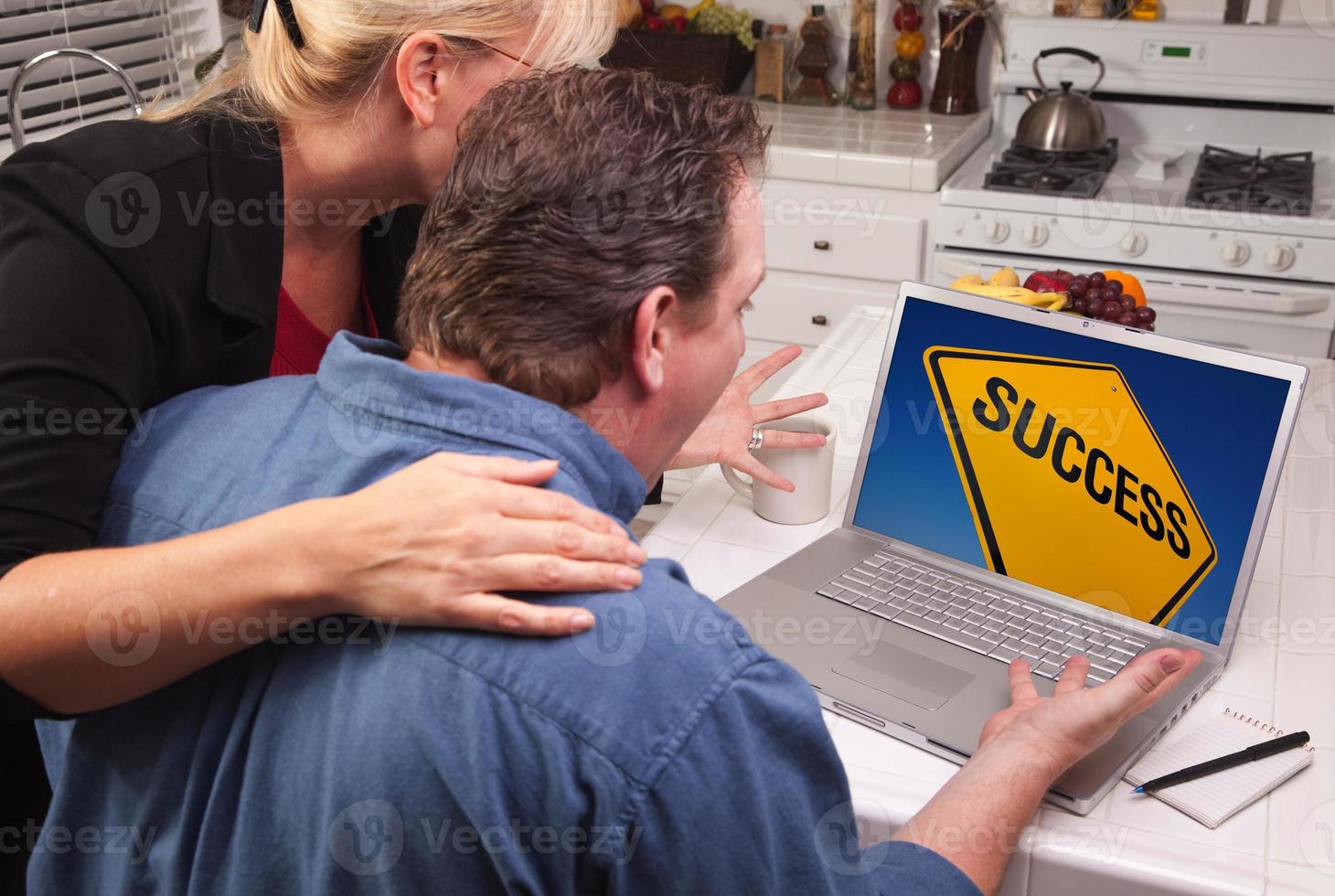 Couple In Kitchen Using Laptop - Success Sign photo