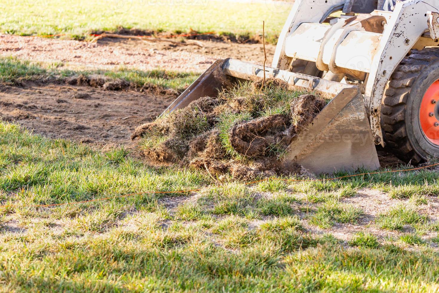 excavadora pequeña quitando hierba del patio preparándose para la instalación de la piscina foto