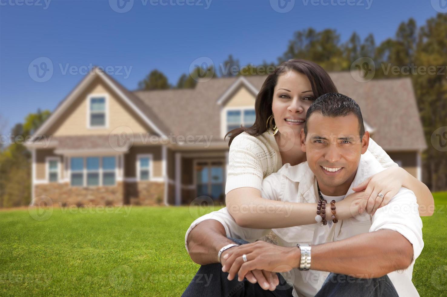 feliz pareja joven hispana frente a su nuevo hogar foto