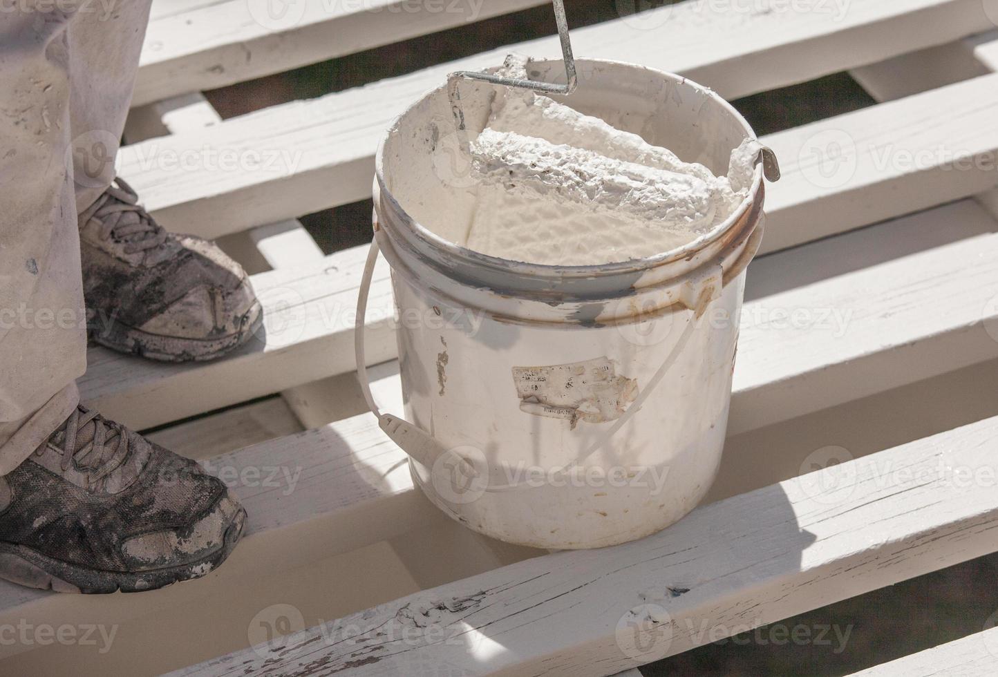 Professional Painter Rolling White Paint Onto The Top of A Home Patio