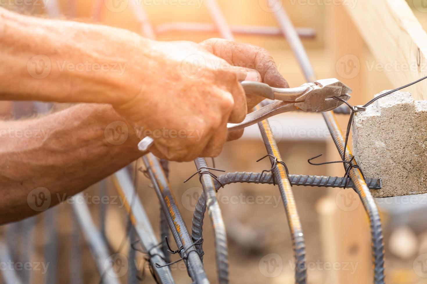 Trabajador que asegura la estructura de barras de refuerzo de acero con la herramienta de corte de alicates de alambre en el sitio de construcción foto