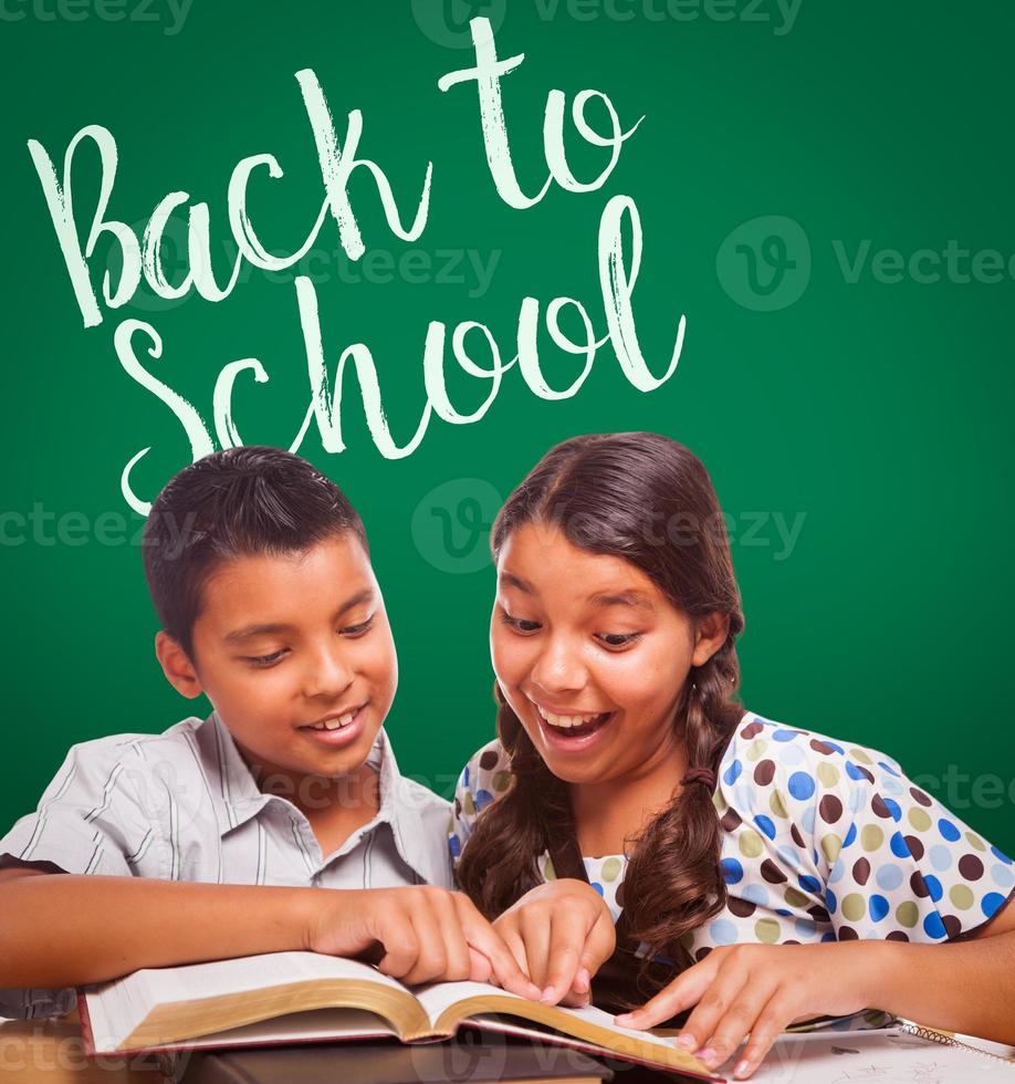 Back To School Written On Chalk Board Behind Hispanic Boy and Girl Having Fun Studying Together photo