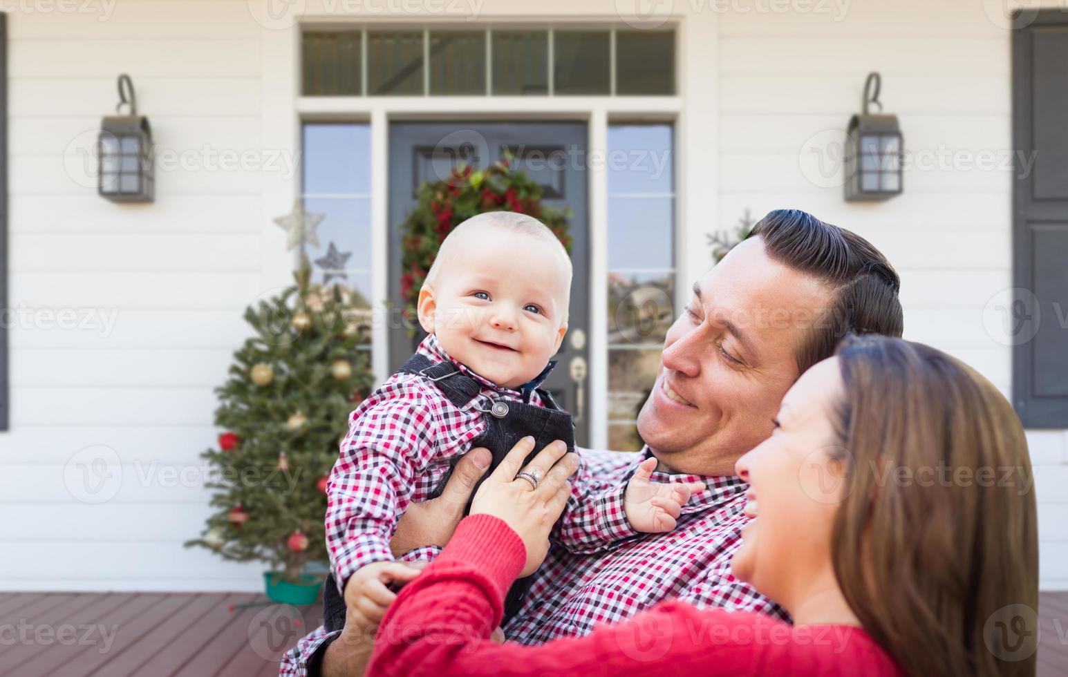 Happy Young Family On Front Porch of House With Christmas Decorations photo