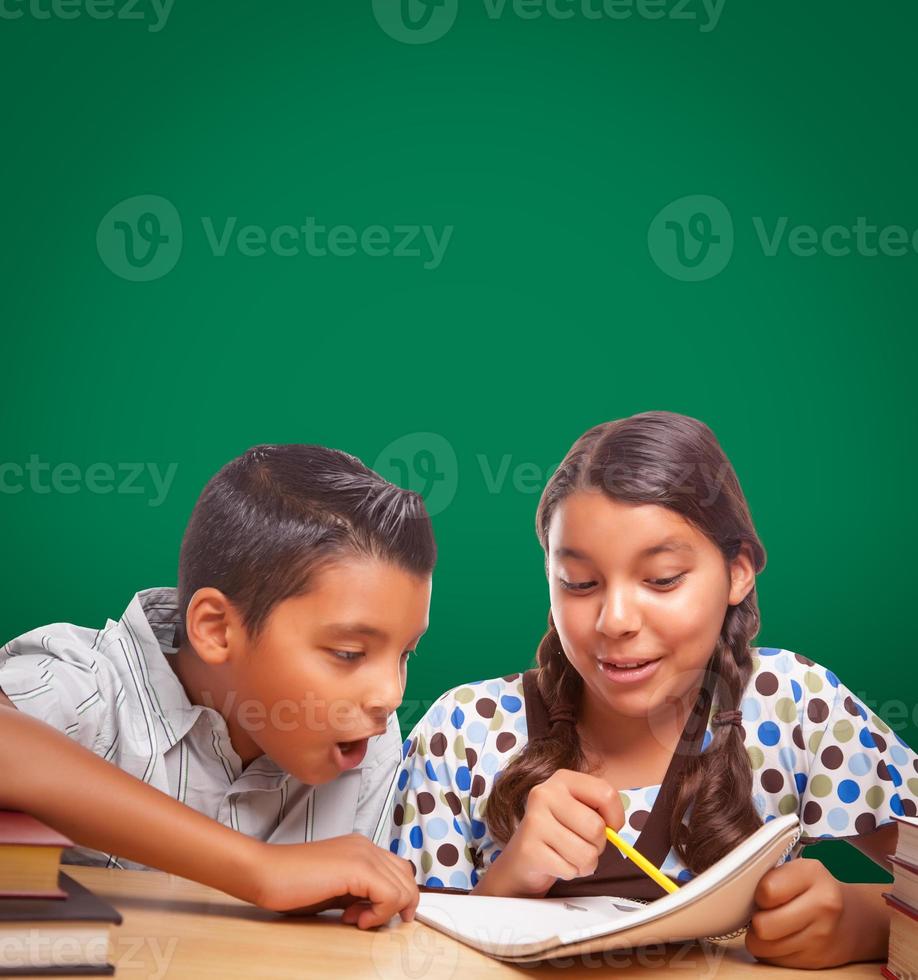 Blank Chalk Board Behind Hispanic Boy and Girl Having Fun Studying Together photo