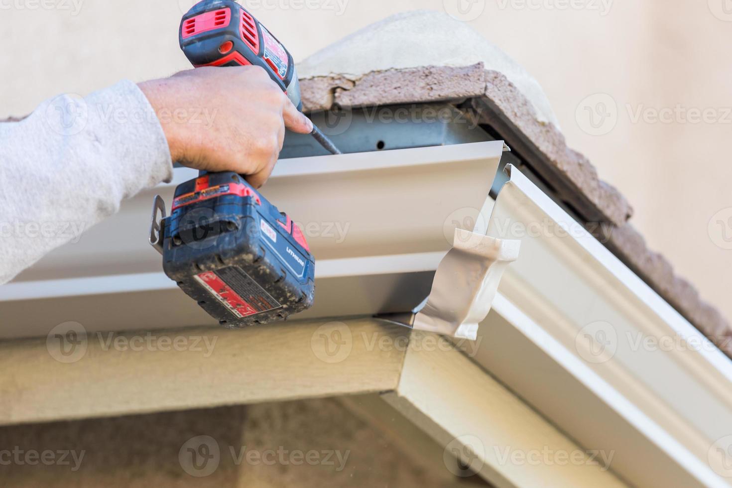 Worker Attaching Aluminum Rain Gutter to Fascia of House. photo