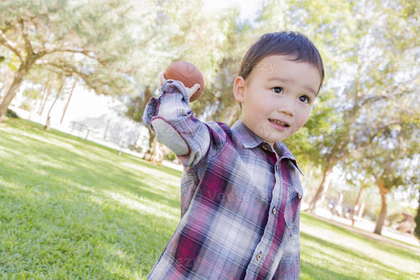 Mixed Race Boy Playing Football Outside photo