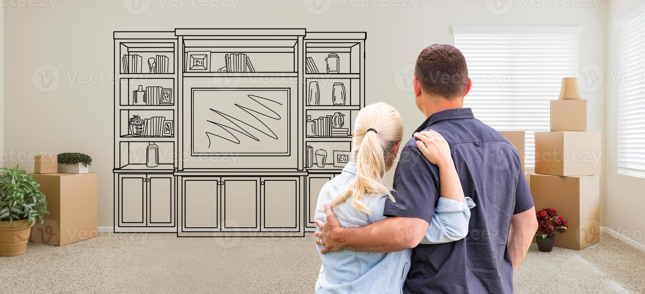 Couple Inside Empty Room with Moving Boxes Facing Entertainment Unit Drawing on Wall photo