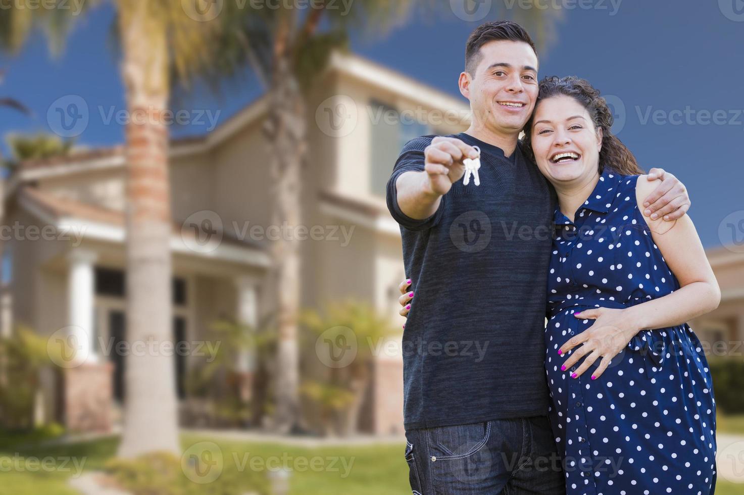 pareja hispana con llaves de casa frente a un nuevo hogar foto