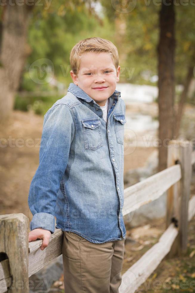 Handsome Young Boy Against Fence in Park photo