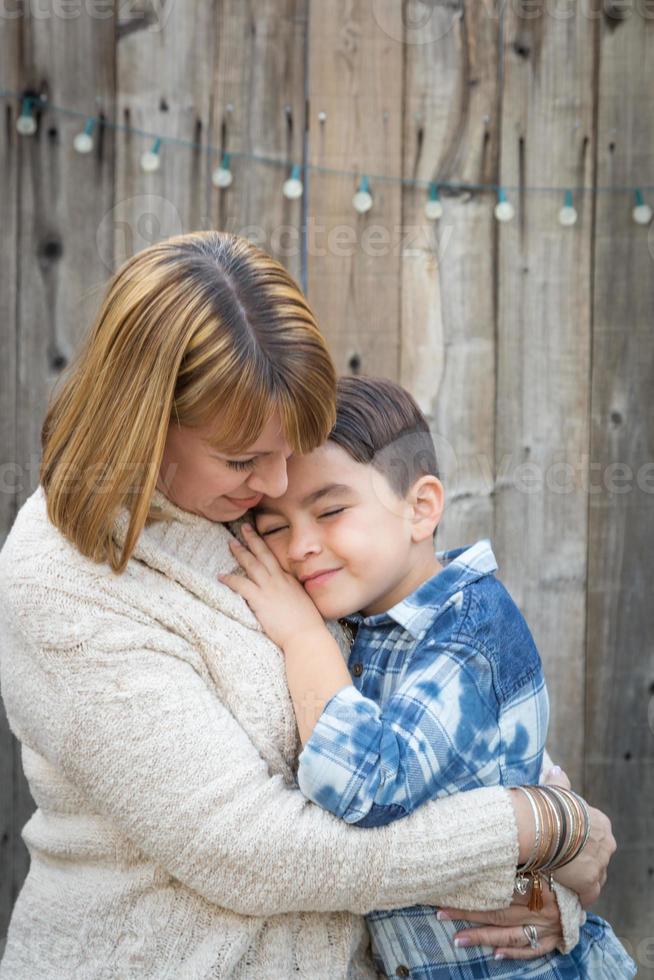 Mother and Mixed Race Son Hug Near Fence photo