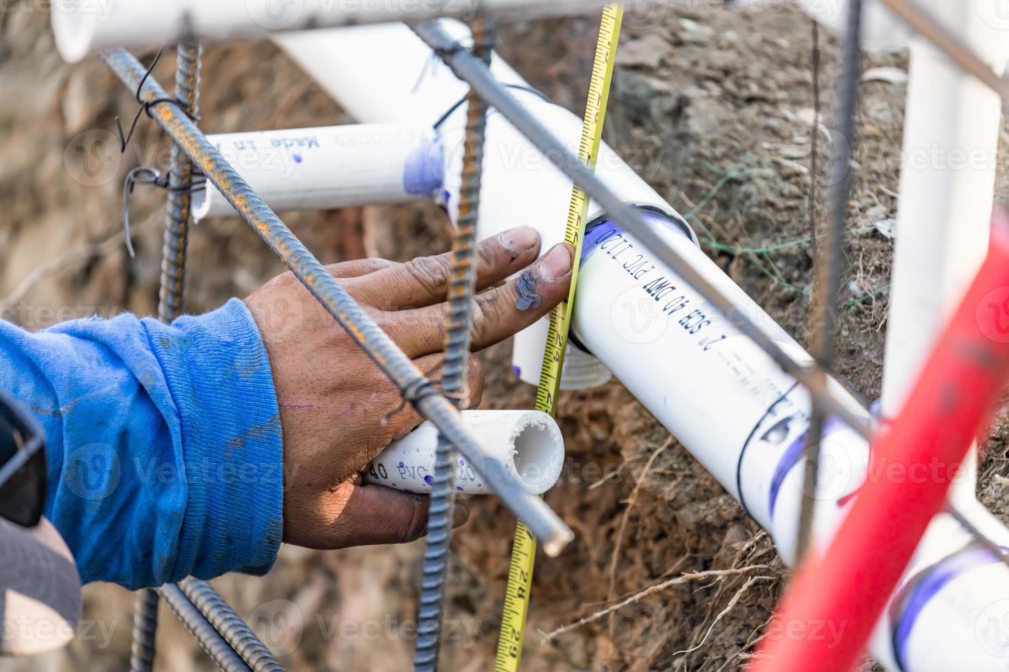 Plumber Using Tape Measure While Installing PVC Pipe At Construction