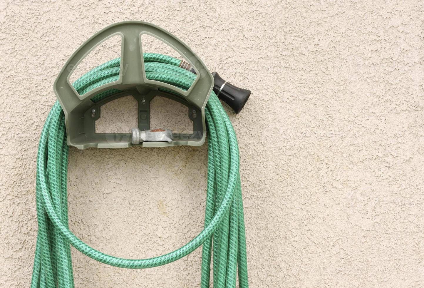 Garden Hose Hanging on Stucco Wall photo