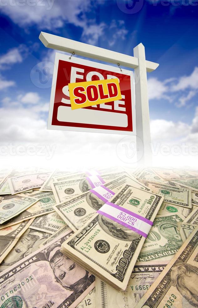 montones de dinero se desvanecen y se venden en venta signo de bienes raíces foto