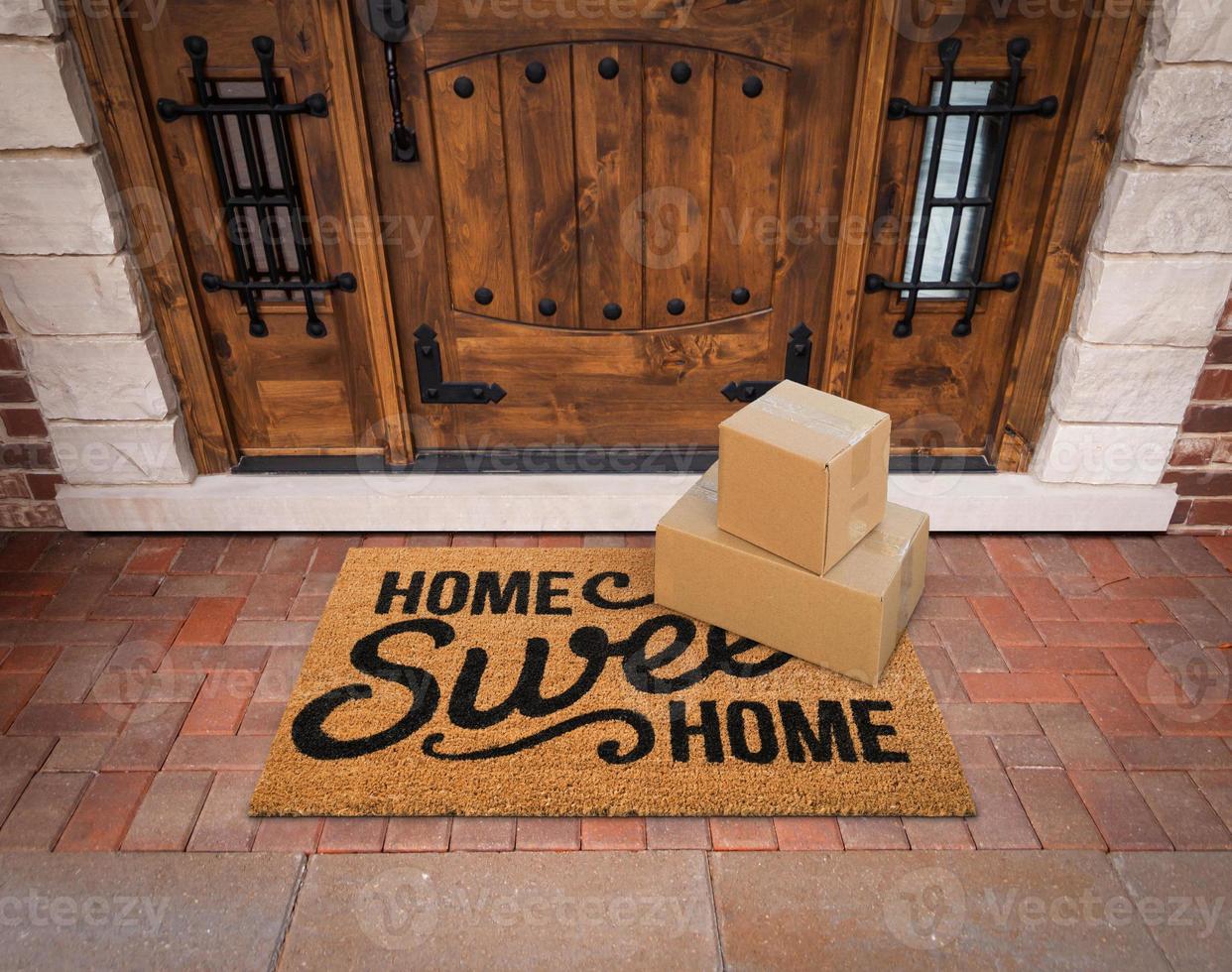 Small Packages Sitting on Home Sweet Home Welcome Mat At Front Door of House. photo