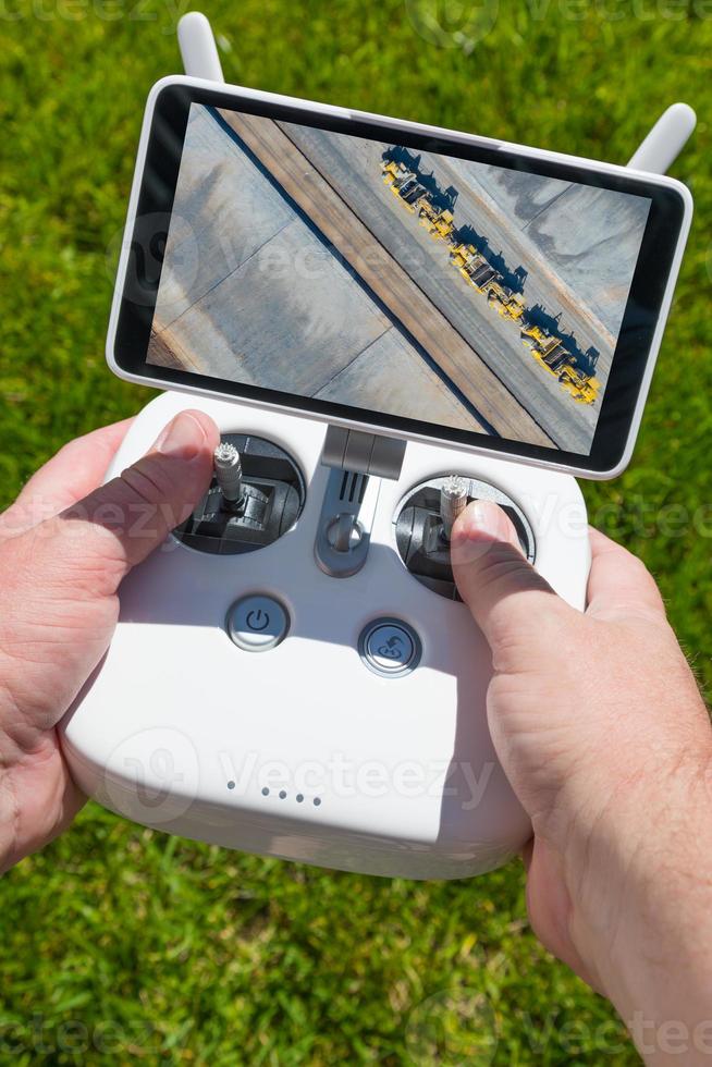 manos sosteniendo el controlador de drones quadcopter con sobrecarga de tractores en la pantalla foto