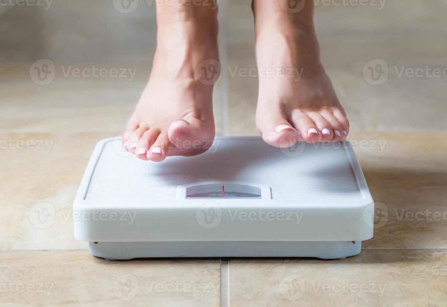 Woman Floating Slightly Above Surface of Weight Scale photo